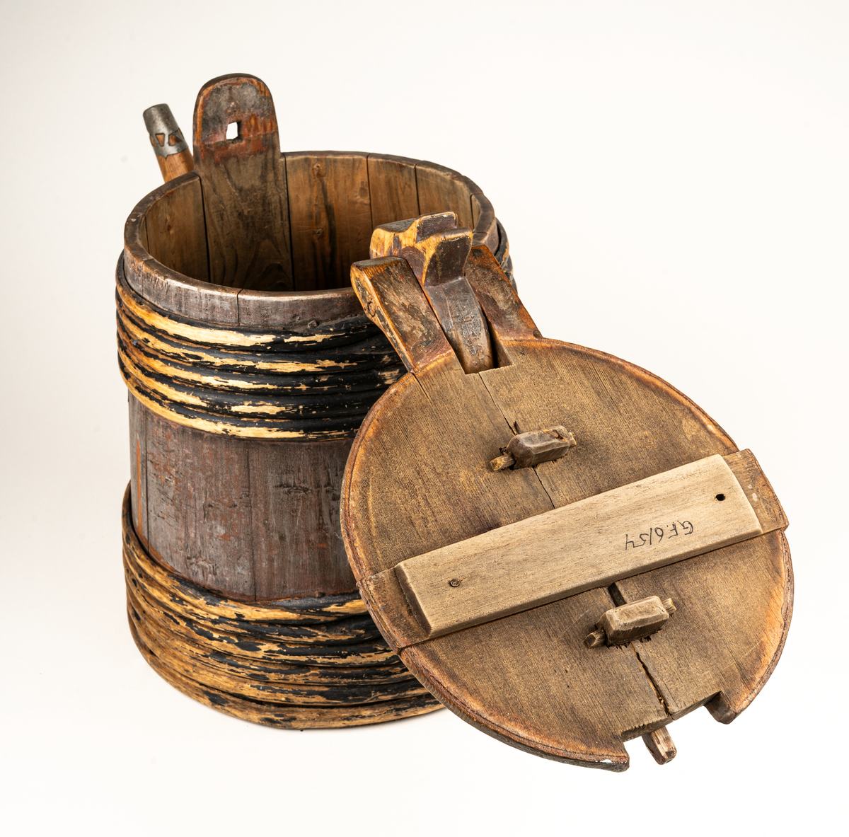 Stånka, laggad, med 11 träband. Med naturvuxen lång pip med blybeslag i änden. Locket har handtag samt horisontell stav, som kan låsa stånkan genom instickning.