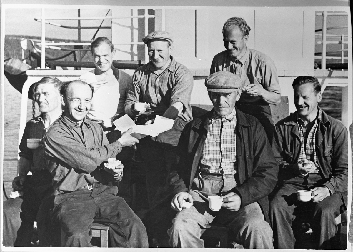 Mannskap på D/S Thor på Mjøsa.
1. rekke: 1. Oskar Westby, Espa, tømmerfølger.  2. Simen Evensen, Nes på Hedmark, styrmann,  3. Sverre Vilberg, Nes på Hedmark, kokk.
2. rekke:  1 Ukjent, fyrbøter.  2. Syver Olsen, Fredrikstad, fyrbøter.  3. Kåre Sundbakken, kaptein.  4. Kristian Kristiansen, tømmerfølger.
Her drikkes det kaffe med kaker.  Brun spanderte.  Det var journalist Brun i Dagbladet som hadde leiet et fly og landet på Mjøsa og entret båten.  Maskinist Skafterød var også mannskap ombord, men var nede i lugaren sin da han hadde frivakt.  Da Kåre fortalte at de hadde fått besøk av et fly, trodde han at de bare skrønte, derfor ville han ikke gå opp på dekk, noe han angret etterpå da han jo ikke fikk noe fotografi.