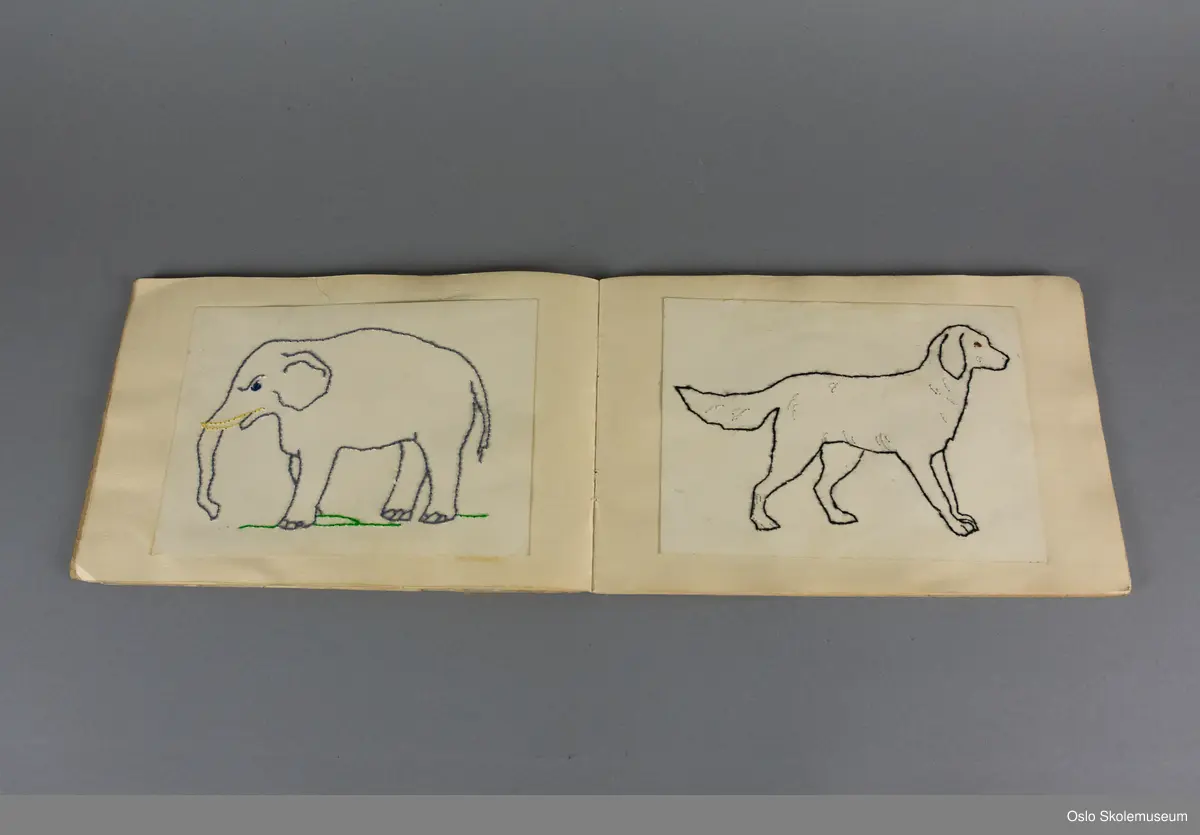 Arbeidsbok i håndarbeid med beige perm. På midten av fremsiden er det en klistrelapp i svart og beige. Inni arbeidsboken er det forskjellige håndarbeidseksempler i pappsøm.