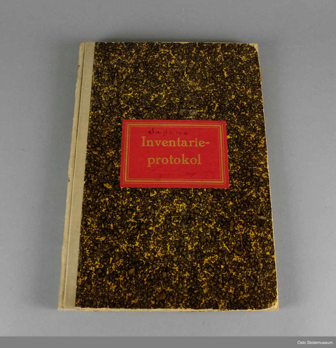 Inventarprotokoll fra skolekjøkkenet på Sagene skole. Boken har brun spraglete perm med beige teip i ryggen. På forsiden er det en rød etikett med gullskrift. I boken er det forhåndstrykte ruter og tekst samt håndskrevet tekst med oversikt over inventaret på Sagene skolekjøkken mellom 1926 og 1961.