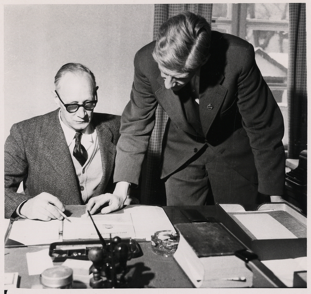 Överkonstapel Henning Johansson och kriminalkonstapel Birger Strandmark på polisstationen, Växjö.

Reportagebild från tidningen "Kronobergaren", 13/2 1954.