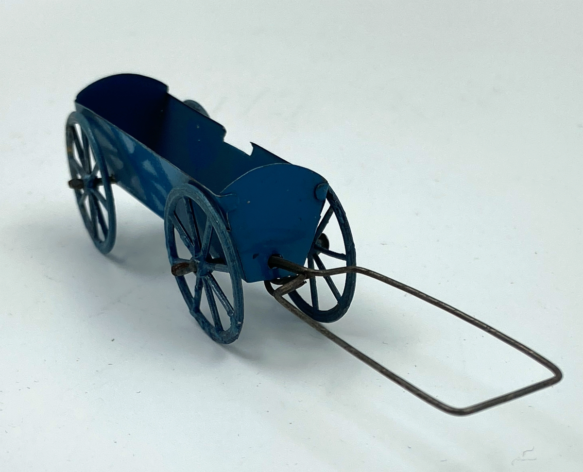 Lastvagn av blåmålad plåt. Höga, svagt utåtlutande lämmar, varav den bakre och främre med välvd överkant. Fyra ekerhjul. Drag av rektangulärt formad ståltrådsögla.