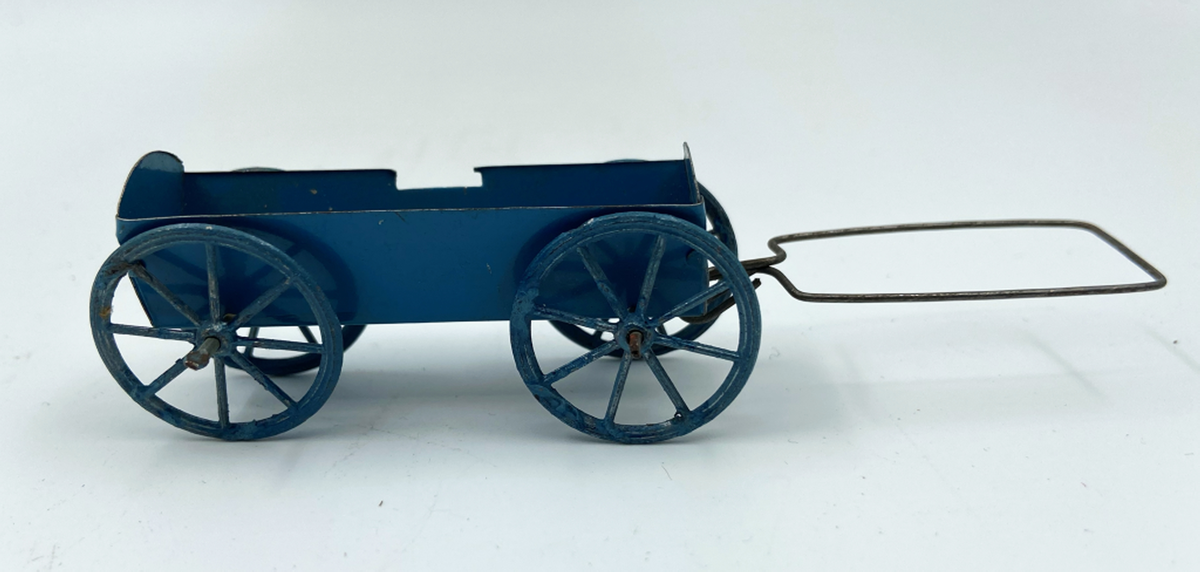 Lastvagn av blåmålad plåt. Höga, svagt utåtlutande lämmar, varav den bakre och främre med välvd överkant. Fyra ekerhjul. Drag av rektangulärt formad ståltrådsögla.