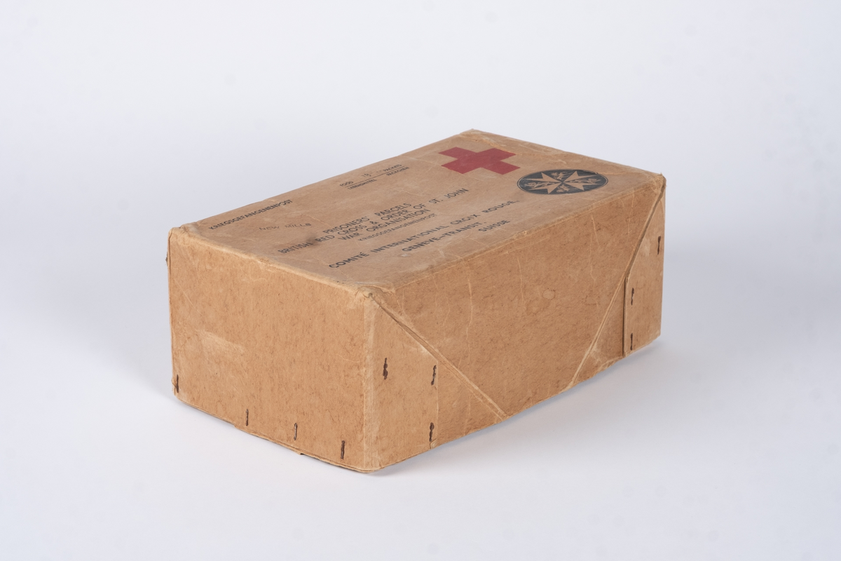 En eske av papp bestående av lokk og bunn. På oversiden av lokket er det påført tekst og logoer. I bunnen av esken ligger det tynt papir med prikker på. 