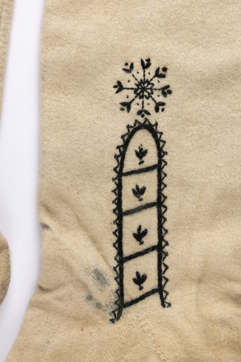 Hvite sydde strømper av vadmel med brodert dekor i svart.