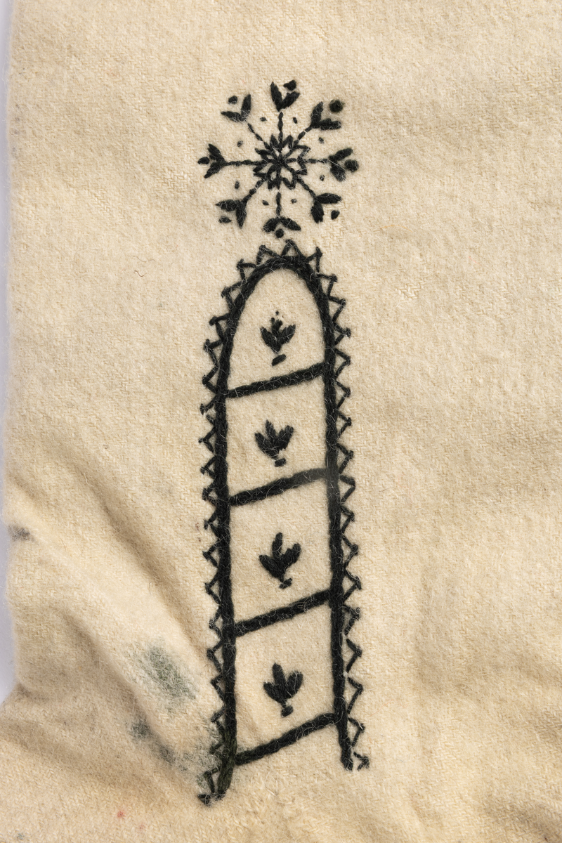 Hvite sydde strømper av vadmel med brodert dekor i svart.