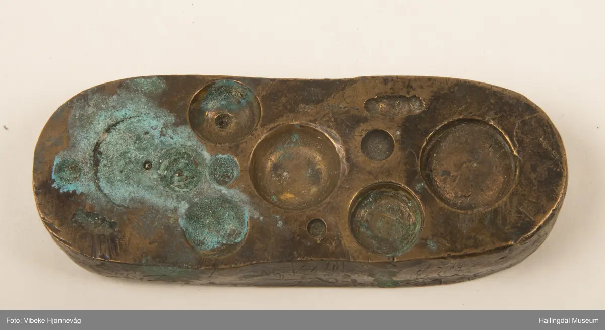 Støpeform i messing til sølvarbeid. Oval med groper og former på begge sider. Tekst: M.E. 830 S 1868. L: 10 cm, B: 3,8 cm, H: 1,5 cm.