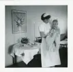 Fotografi på ett dop av Michel på Lilla Källbäck med barnsköterska som håller honom, 1959.
