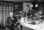 Man sitter vid bord med blommor, Alunda, Uppland