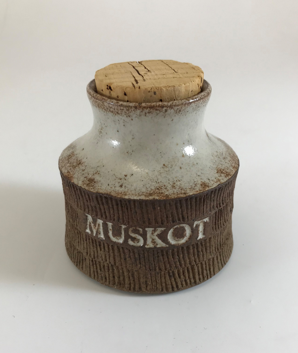 Signe Persson-Melin, burk med korklock, stengods i vit och brunprickig glasyr, nedre delen oglaserad, ristad dekor, stämplad MUSKOT. Tillverkning: Egen verkstad, Malmö, 1950-talets första hälft.