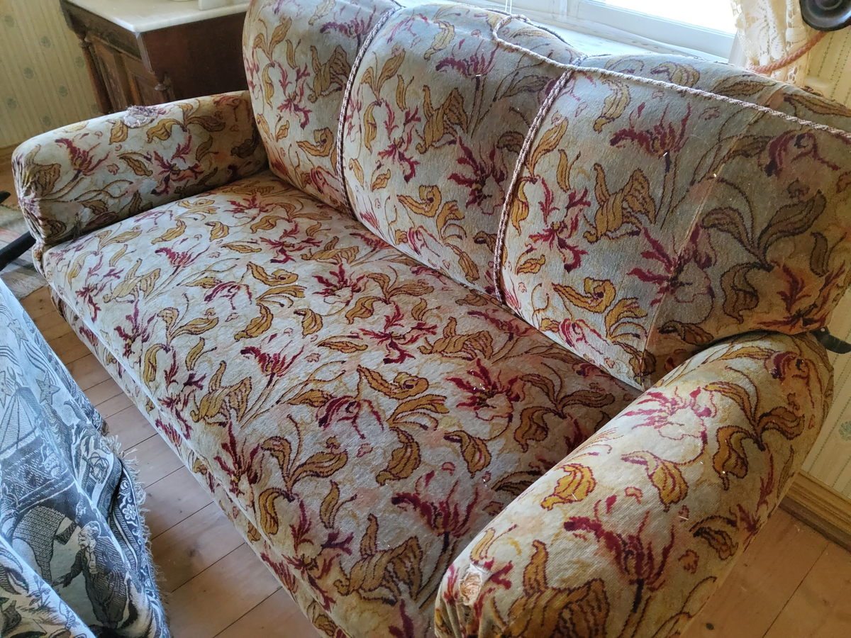 Soffa, helt stoppad  med svarvade kulfötter. Helt klädd i blommig schagg i rött och gult mot beigebrun botten.