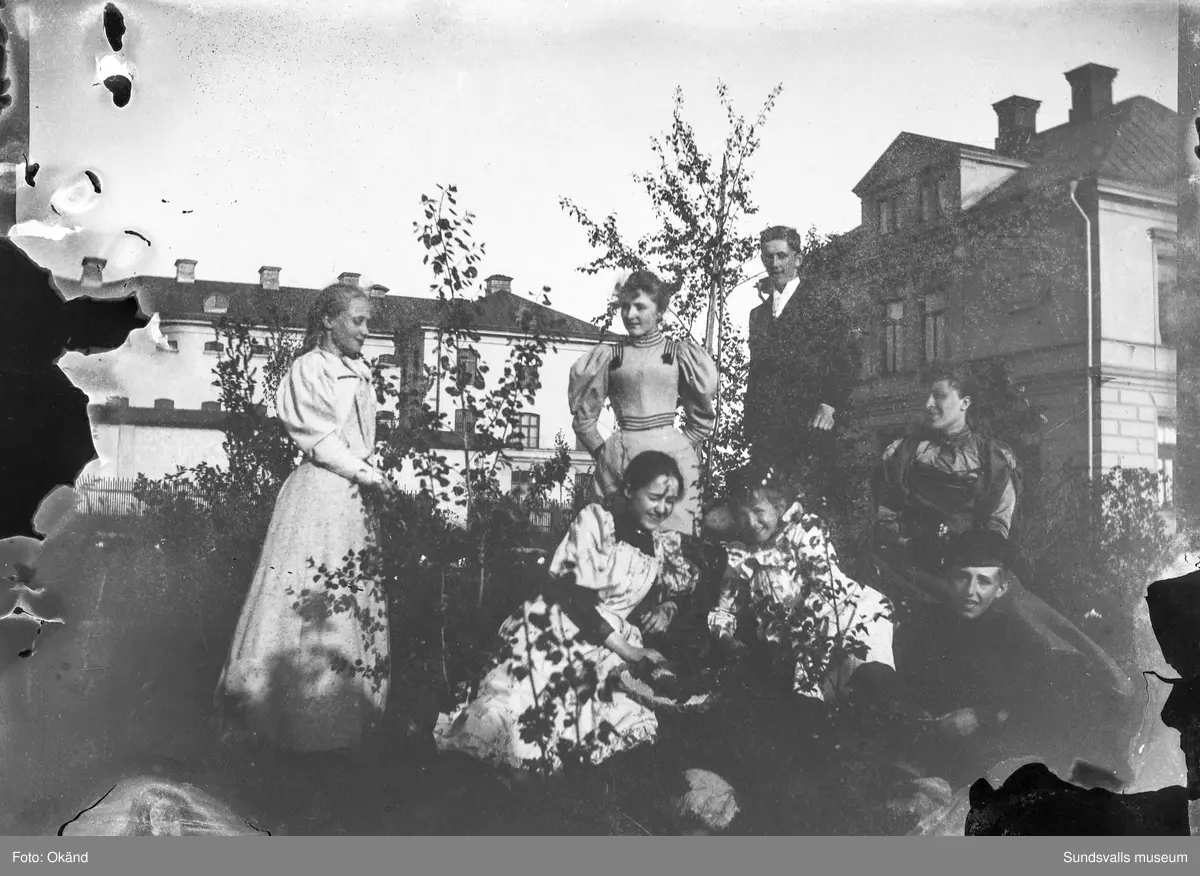 Carl Theodor och Blanche Lindahls barnaskara i trädgården vid villan på Åkersvik (mellan Västra Domsaga och Kronohäktet). Barnen heter Tyra, Signe, Erik Olof, Harald, Frida, Herman och Elsa. I bakgrunden syns Kronohäktet.