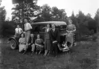Foto av några personer på utflykt. De har samlats runt sällskapets bil.