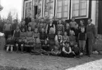 Foto av en skolklass med två lärare, som samlats utanför skolan.