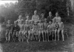 Foto av en grupp pojkar i badbyxor m.m.
Simskola (?).