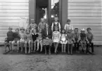 Foto av en skolklass med lärarinna, som samlats utanför skolan.