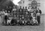 Foto av en skolklass med två lärare, som samlats utanför en kyrka.