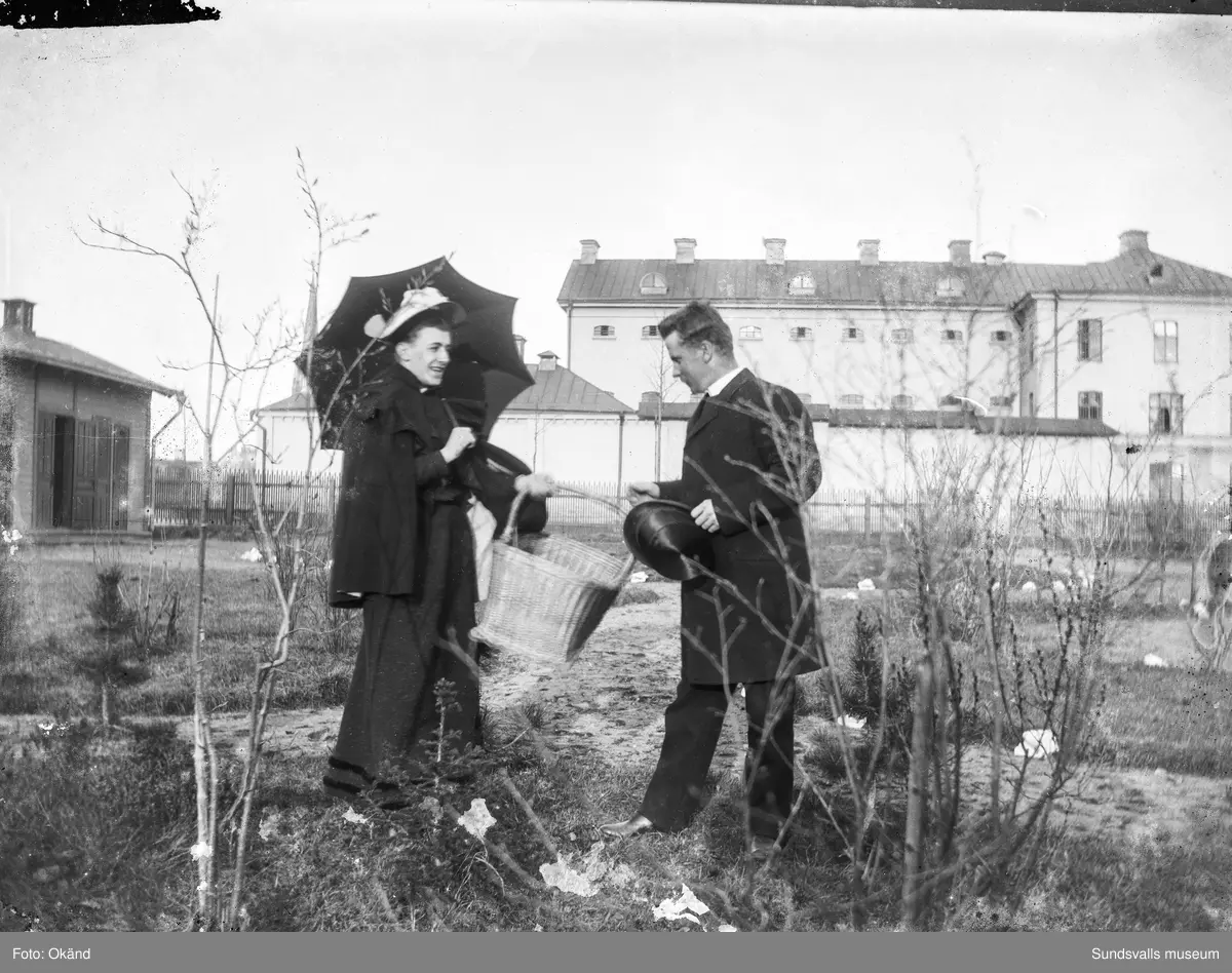 En kvinna och en man i Carl Theodor Lindahls trädgård på Åkersvik. I bakgrunden syns Kronohäktet.