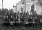 Foto av en skolklass med lärare, som samlats utanför en kyrka.