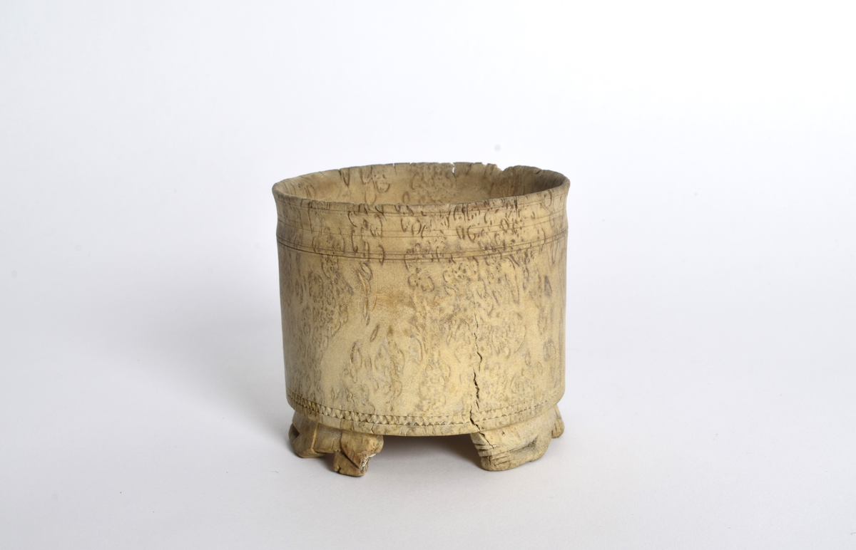 Sukkerkopp (?) i valbjørk. Dreid. Sylindrisk form, flat bunn. Rundt øverste kant, markerte dreiespor. Nederst, en innskåret, smal siksakbord. Står på tre bein som er skåret ut som liggende løver.