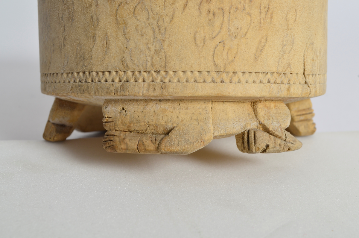 Sukkerkopp (?) i valbjørk. Dreid. Sylindrisk form, flat bunn. Rundt øverste kant, markerte dreiespor. Nederst, en innskåret, smal siksakbord. Står på tre bein som er skåret ut som liggende løver.