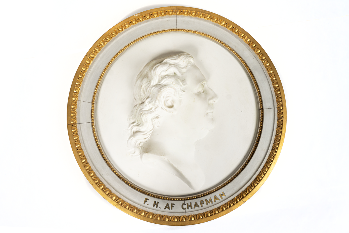 Porträttsmedaljong F.H. af Chapman, gips, förgylld ytter- och innerkant. Osignerad. Sannoligt kopia efter Sergels medaljong av Chapman.