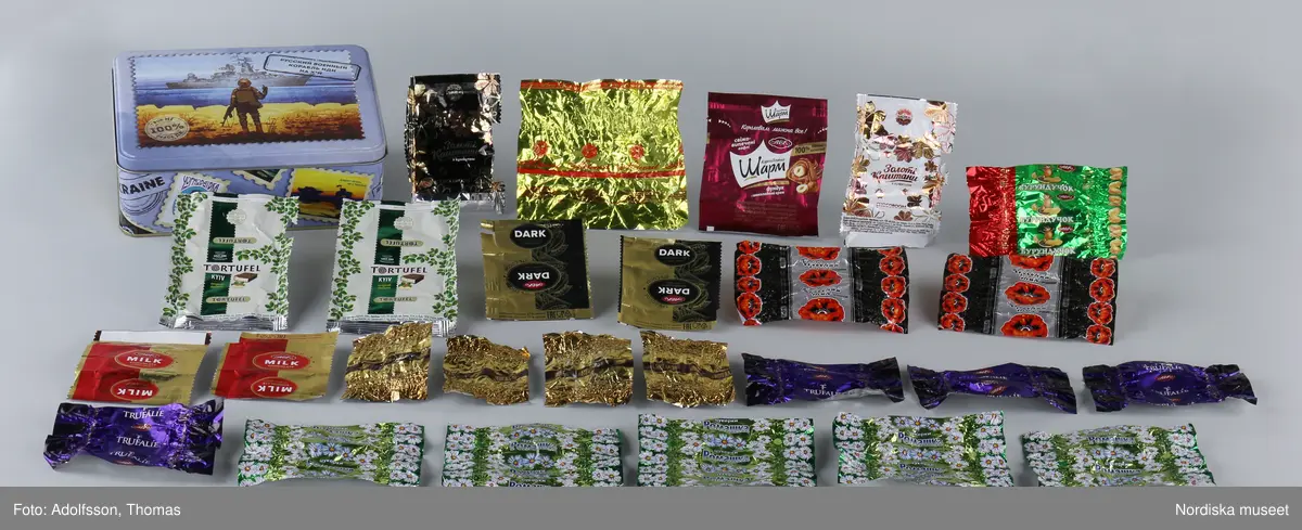 Kolorerad plåtask med lock avsedd för chokladpraliner. Asken är dekorerad med flera olika bildmotiv i blått, brunt, svart, gult och orange. Inuti asken finns 26 omslagspapper till chokladpralinerna i olika färger och mönster.
Motivet på askens lock heter "Russian warship, go...! Glory to Ukraine!". I mitten syns en ukrainsk soldat som skulle kunna vara gränsvakt. Ute på havet framför soldaten syns ett ryskt krigsskepp som kan identifieras som misilkryssaren Moskva byggd 1982. Den ukrainska soldaten är vänd mot skeppet. I sin vänstra hand håller han ett maskingevär och med den högra handen gör han en obscen gest mot fartyget.