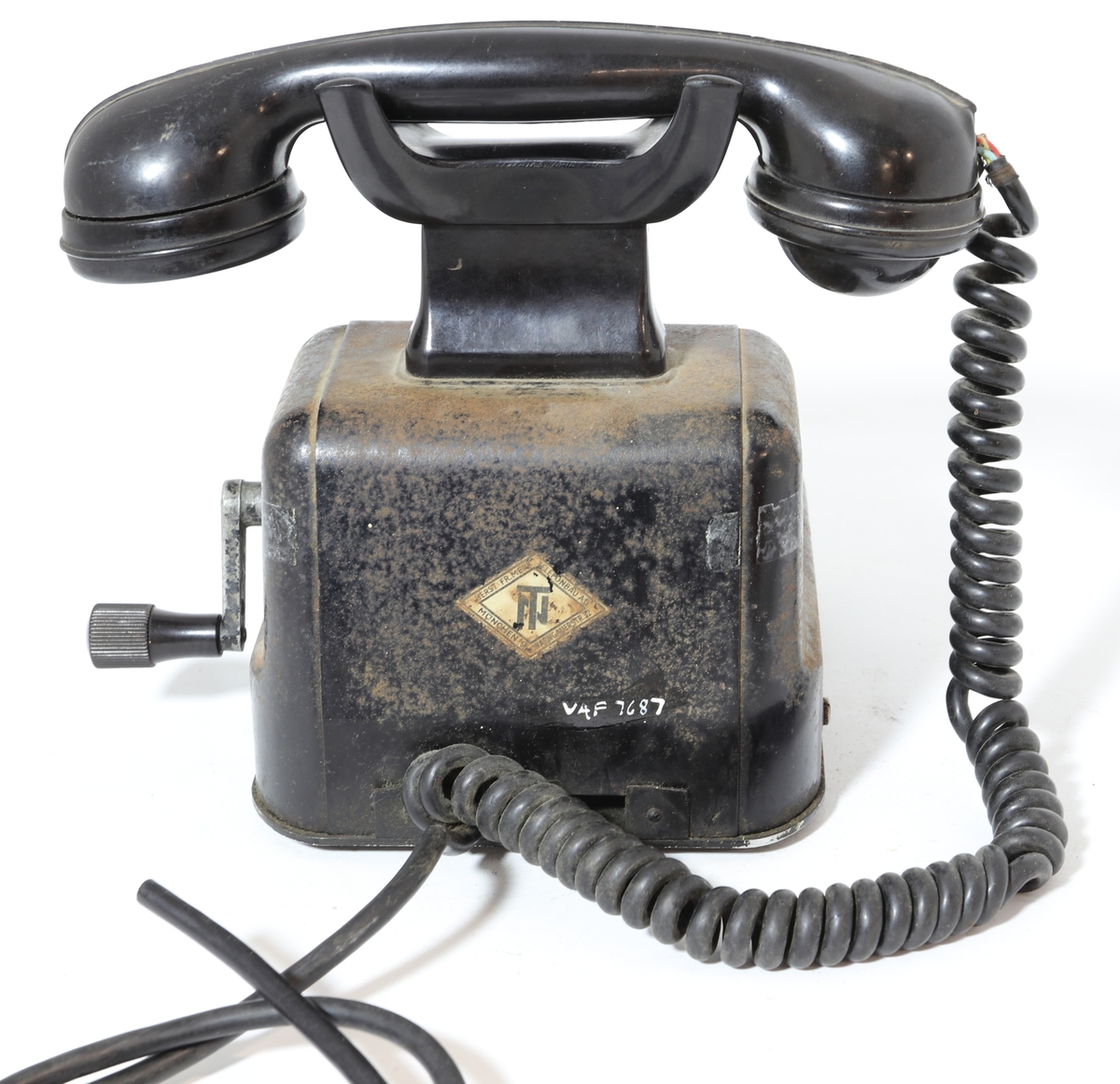 Telefonapparat for manuell sentral, brukt på setesdalsbanen. Apparatet har rektangulær bunn, rette sider, og skrå forkant med flat topp.  Det er en sveiv på siden, og ramme i front med plastdeksel.