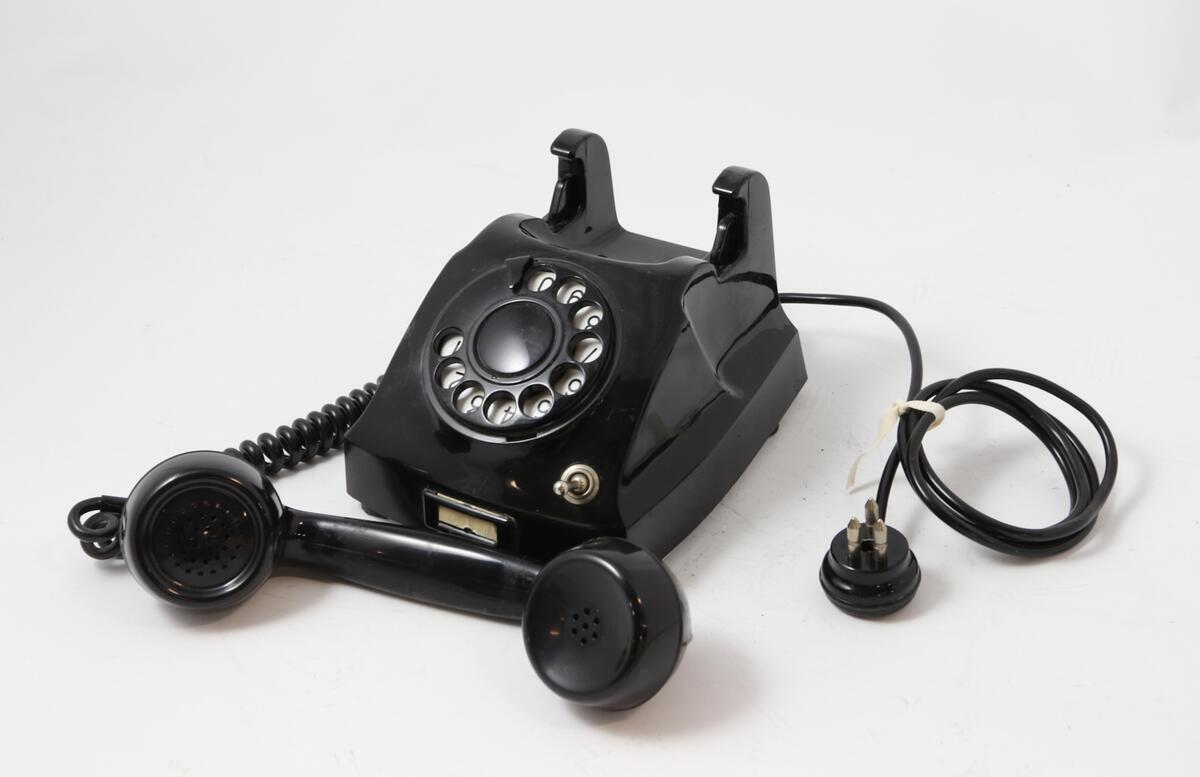 Svart bordtelefon med tallskive og bryter for å slå av inngående ringesignal
