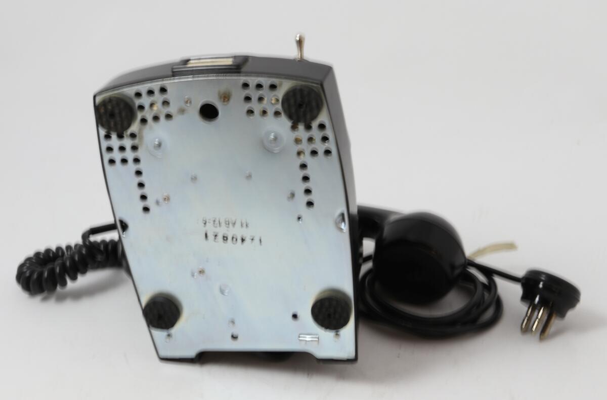 Svart bordtelefon med tallskive og bryter for å slå av inngående ringesignal

