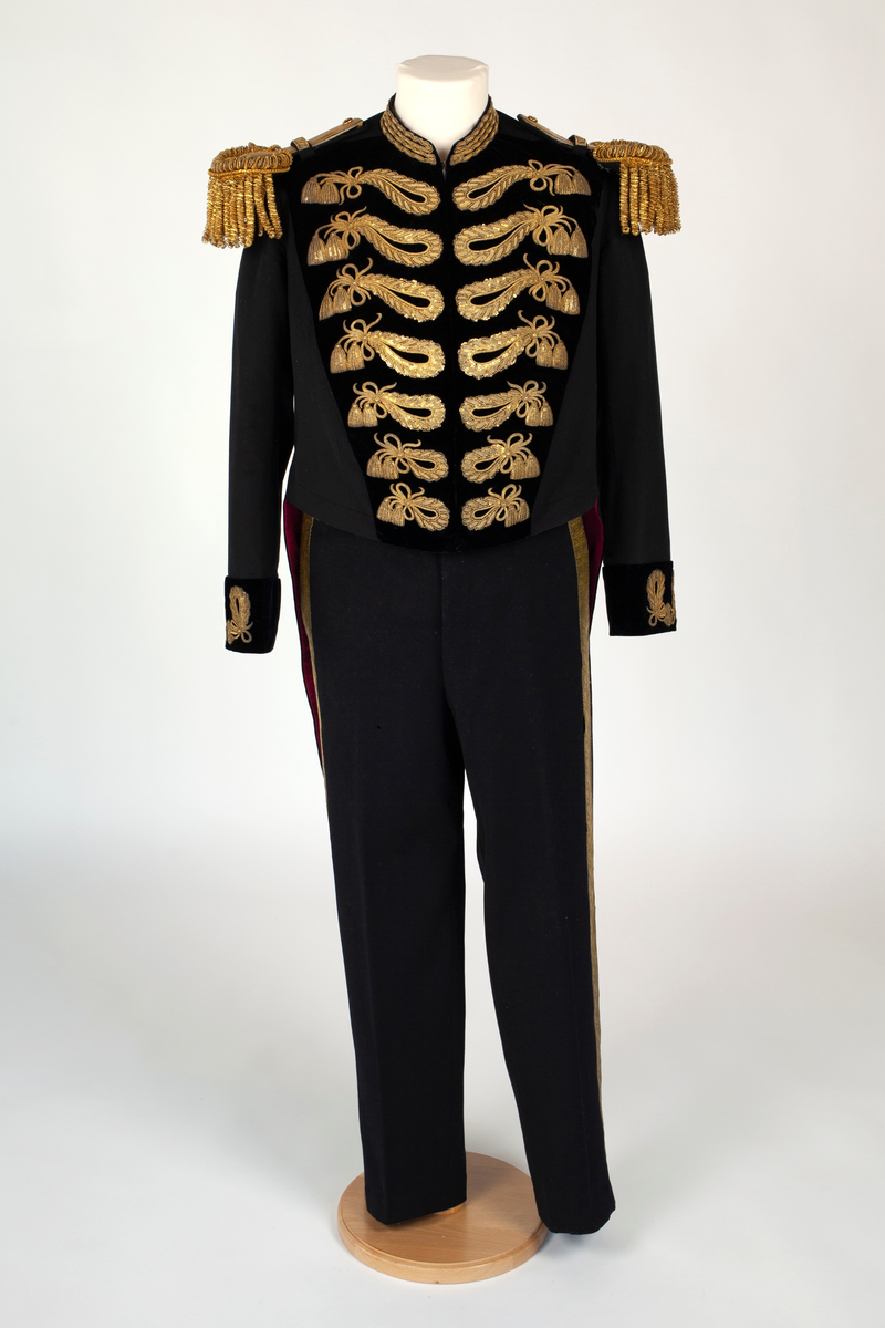 Uniform bestående av frakk og bukse av svart ullstoff. Frakken har korte forstykker som hektes sammen i fronten. Ryggen er figursydd og delt i livet og med skjøter og splitt. På forstykker og på ermene belegg av mørkeblå fløyel med sløyfer av gullinnvevde tresser. Lignende ornamenter på skjøtenes lommeklaffer og over splitten bak. Gule metallknapper med kronet dansk riksvåpen under lommeklaffene og ved splitten. Oppstående krage med fløyelsbelegg og rader av gulltresser på sidene av kragen. Gull-epåletter med frynser. Frakken er fôret med karmosinrød silke, ermene har hvit fôr. Bukse av samme ullstoff med gylfknepping, tamp i ryggen og rette ben med gullgalon langs sidesømmen; 5 cm bredt bånd med innvevd dobbelt eikeløvsranke. Ved buksebenskanten knapper for elastisk bånd (under skoen).