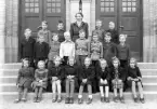 Foto av en skolklass med lärarinna, som samlats utanför skolans port.