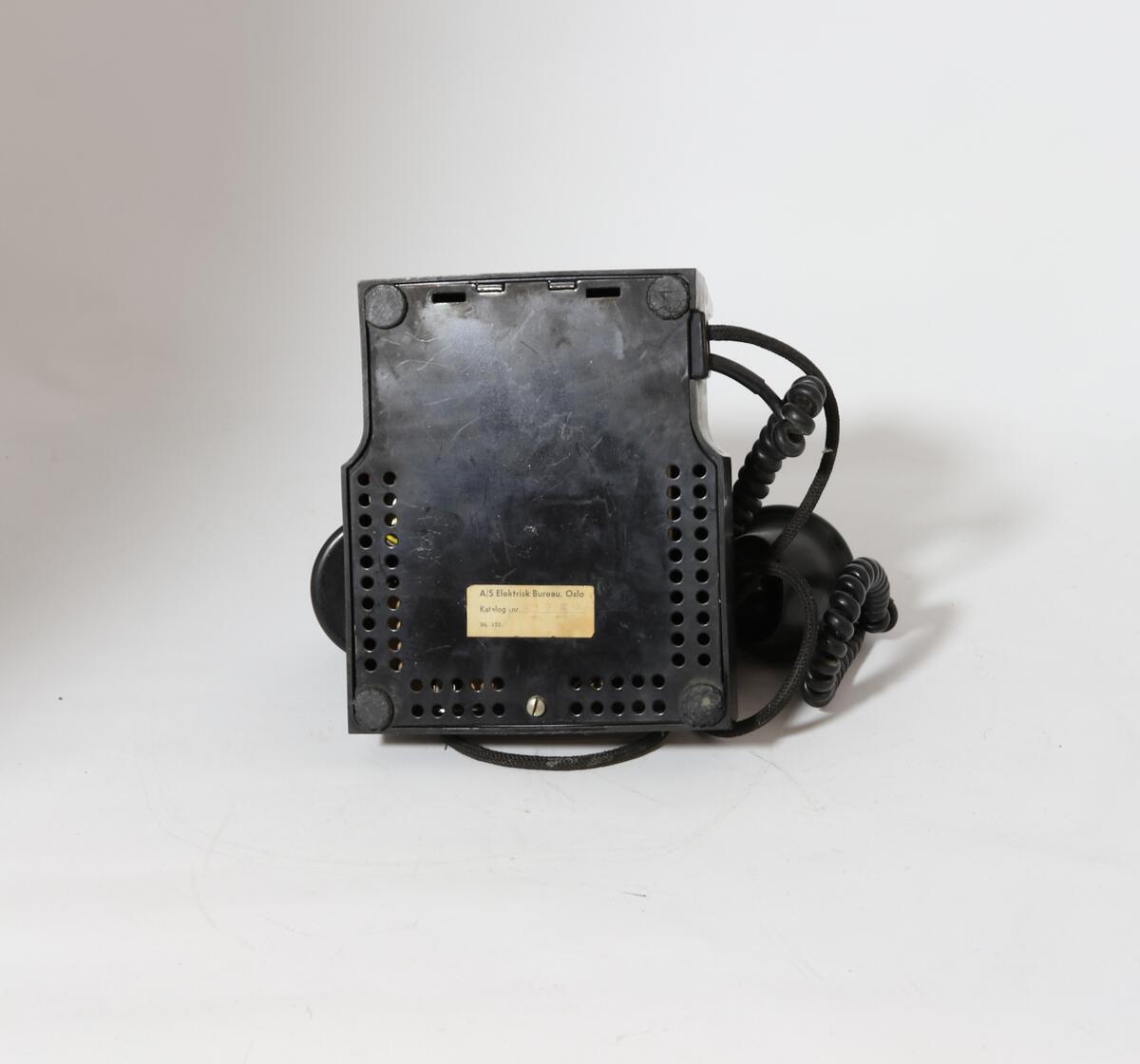 Vanlig bord-telefon med trykknapp under på siden av tallskiven. Telefonen har ekstra intern linje. Er et såkalt sekretærapparat. Telefonen er utstyrt med tekstilsnor til mikrofon og støpsel. To trykknapper ved gaffelen for intern linje.
