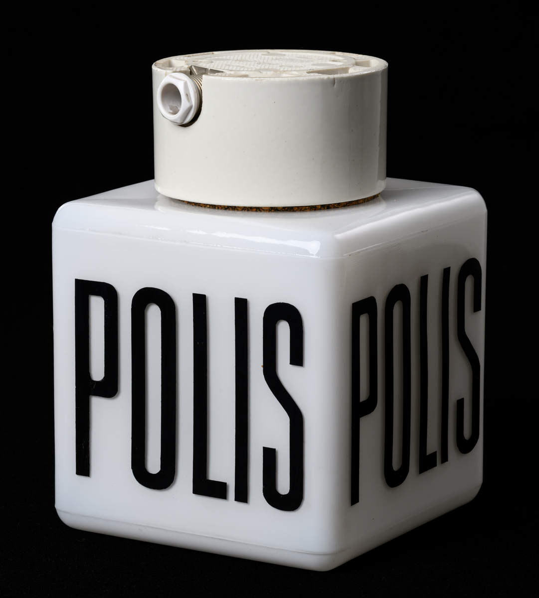 Takarmatur/fasadbelysning. Kubformad opal glaskupa med texten POLIS kupans väggar. Cylindrisk vit porslinssockel.