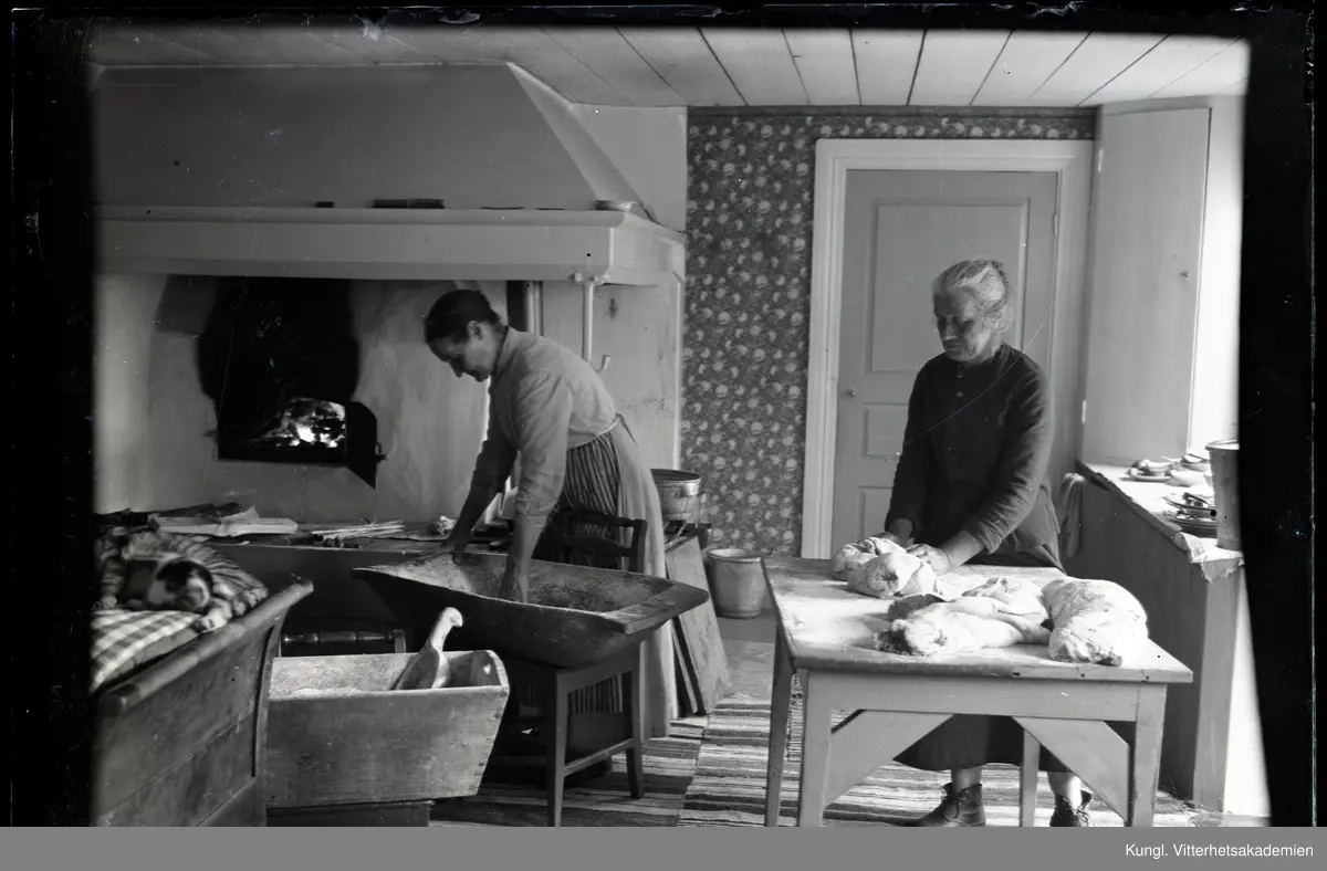 Tilia Andersson och en äldre kvinna bakar bröd. Tilia står lutad över ...