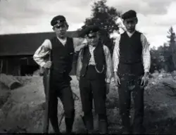 Tre pojkar i Stensjö by. Till vänster är Bengt Stensiö med gevär i handen. Till höger står Eugén Stensiö. I bakgruden syns en lada.