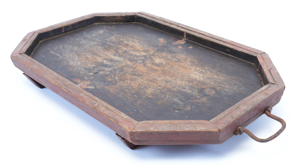 Toppen av brettet er måla svart på innsida, med ei raud ramme rundt. Midt på toppen er det spor etter rosemåling (raude blad). Føtene under brettet er utskorne i form av to voluttar som vender mot kvarandre (hjarteform i midten).