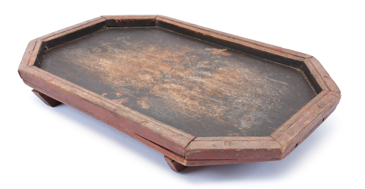 Toppen av brettet er måla svart på innsida, med ei raud ramme rundt. Midt på toppen er det spor etter rosemåling (raude blad). Føtene under brettet er utskorne i form av to voluttar som vender mot kvarandre (hjarteform i midten).