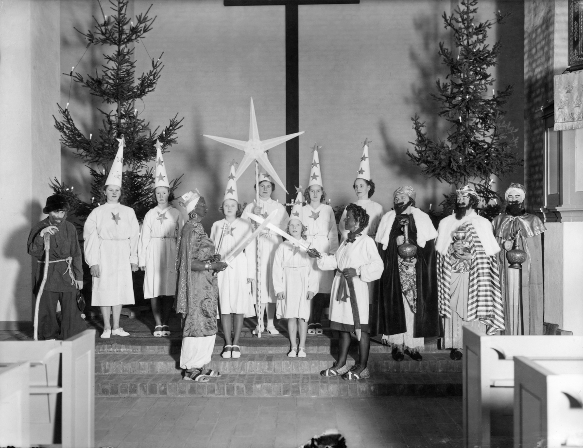 Röda korsets luciatåg i Nynäshamns kyrka. I luciatåget ingår stjärngossar, de tre vise männen, Judas och två figurer till som eventuellt ska föreställa kung Herodes. 

Årshögtider, religion, traditioner, förening.

Personer på bilden:
Kvinna som håller i stjärnan Elsa Åström, kvinnan till höger om henne Hjördis Bjurholm.