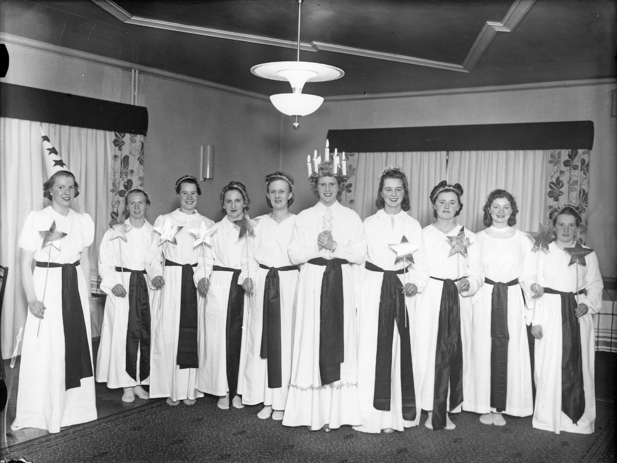 Lottakårens luciatåg på Järnvägshotellet. En lucia med tärnor som har stjärnor i händerna, en flicka har en stjärngossestrut på huvudet. 

Årshögtider, traditioner, förening.

Personer på bilden:
Från vänster 1. Ulla Alexisson (gift Klasson), 2.? 3. Birgit Pettersson (gift Sjödén), 4.?, 5.?,  Maj Grandin, 6. Gun Johansson, 7.?,  8.?, . 9. Märta Johansson