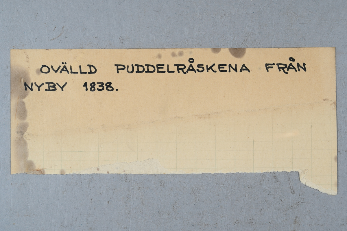 Järnprov. Märkning på provet med påklistrad lapp med notering: "394". Tillhörande lapp med notering: "Ovälld puddelråskena från Nyby 1838."