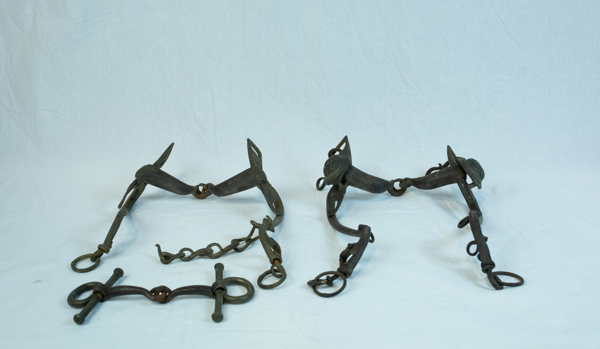 To sett leddet sammen med hyssing. Form: mange ledd er hektet sammen til komplett seletøy b) har boltet inn to "kulekapper" på hver side av hovedleddet. Krone og emblem/ initialer?