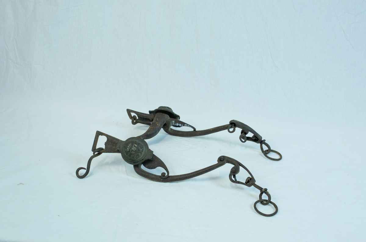 To sett leddet sammen med hyssing. Form: mange ledd er hektet sammen til komplett seletøy b) har boltet inn to "kulekapper" på hver side av hovedleddet. Krone og emblem/ initialer?