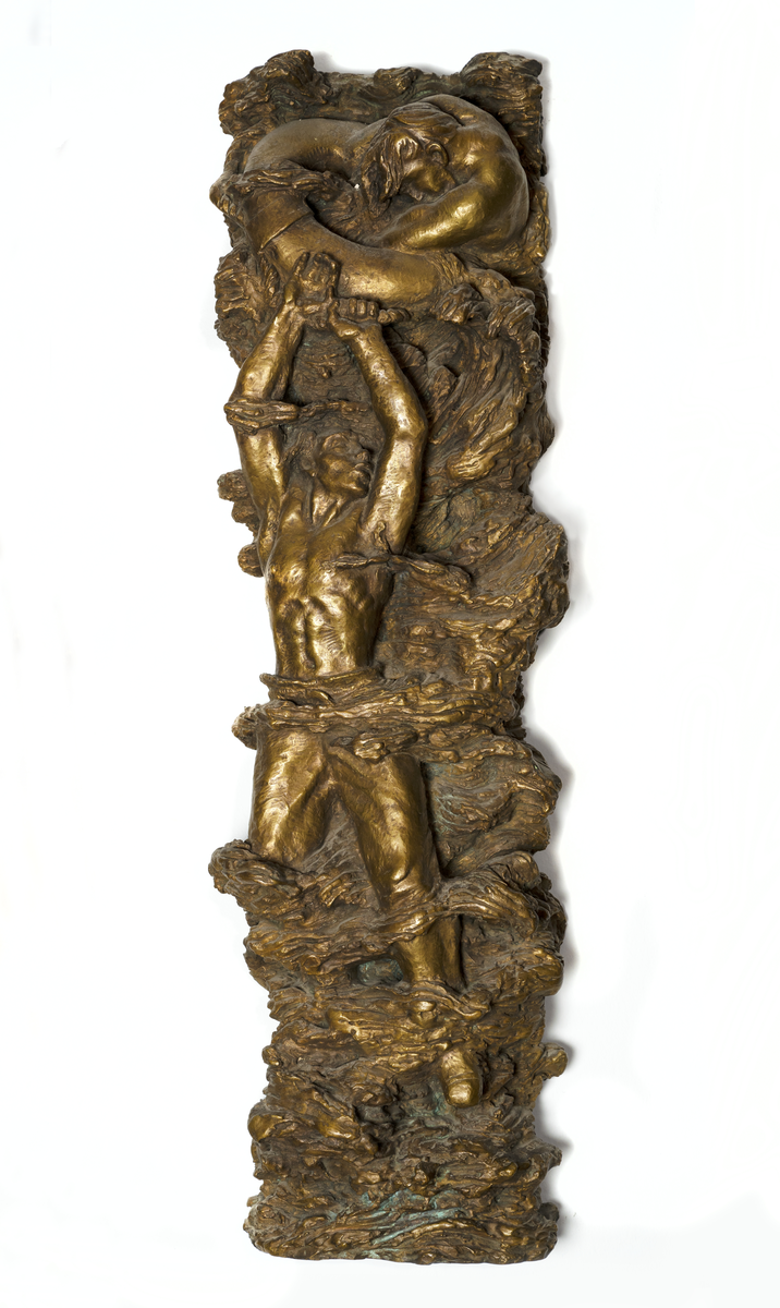 Skulptur av brons i högrelief. Skulpturen symboliserar sjömannens kamp för sitt liv. En sjöman med naken överkropp stående på vrakspillra och lyftande medvetslös kamrat ur skummande vågor. Nederst en bruten mast och upptill måsar.