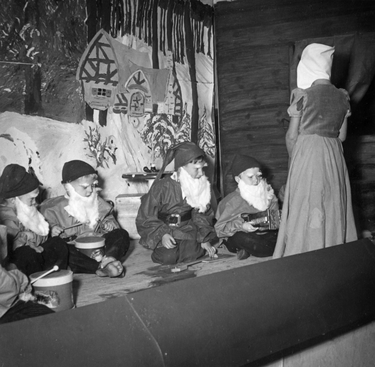 "Muntra fruarnas julmässa", julmarknad i gamla mässen, Cementa, Stora vika. Några barn spelar "Snövit och de sju dvärgarna" på scenen. 

Årshögtider, teater.