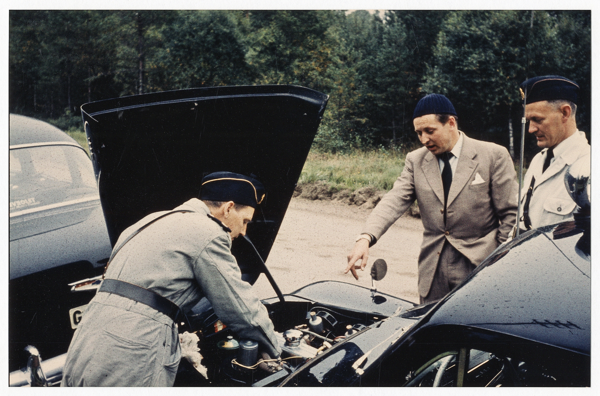 Poliserna Sven Lindgren, K-E Juteström och Evert Petersson inspekterar en bilmotor.