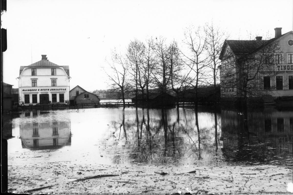 Översvämning i Bollnäs köping 1916. Till vänster Sandberg & Styfs Järnhandel, till höger gamla tingshuset (som senare en tid blev Folkets Hus) och i mitten bron över "Lortbäcken" samt kyrkstallar.