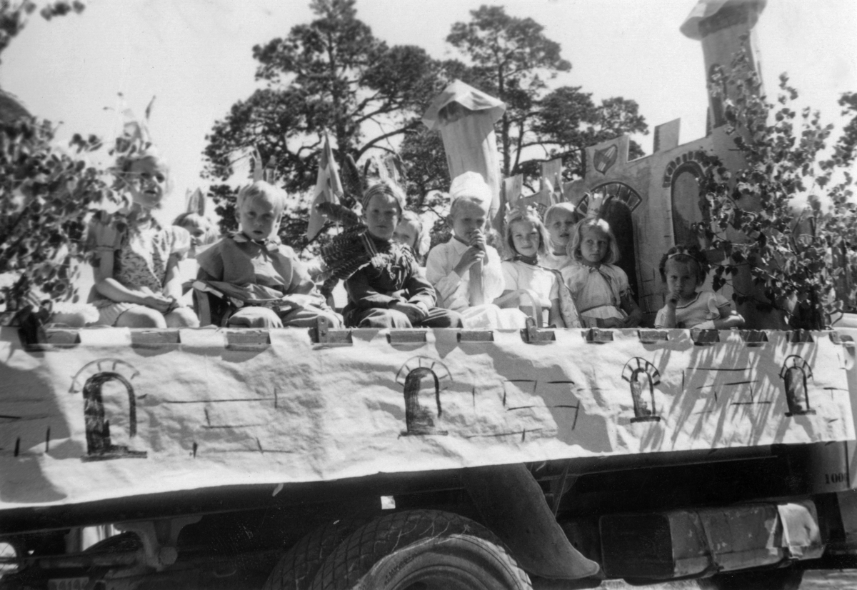Barnens dag. Barn utklädda i maskeradkläder, bland annat prinsessor och prinsar, sitter på en lövad lastbil. 

Nöjen, fritid, traditioner, sommar.