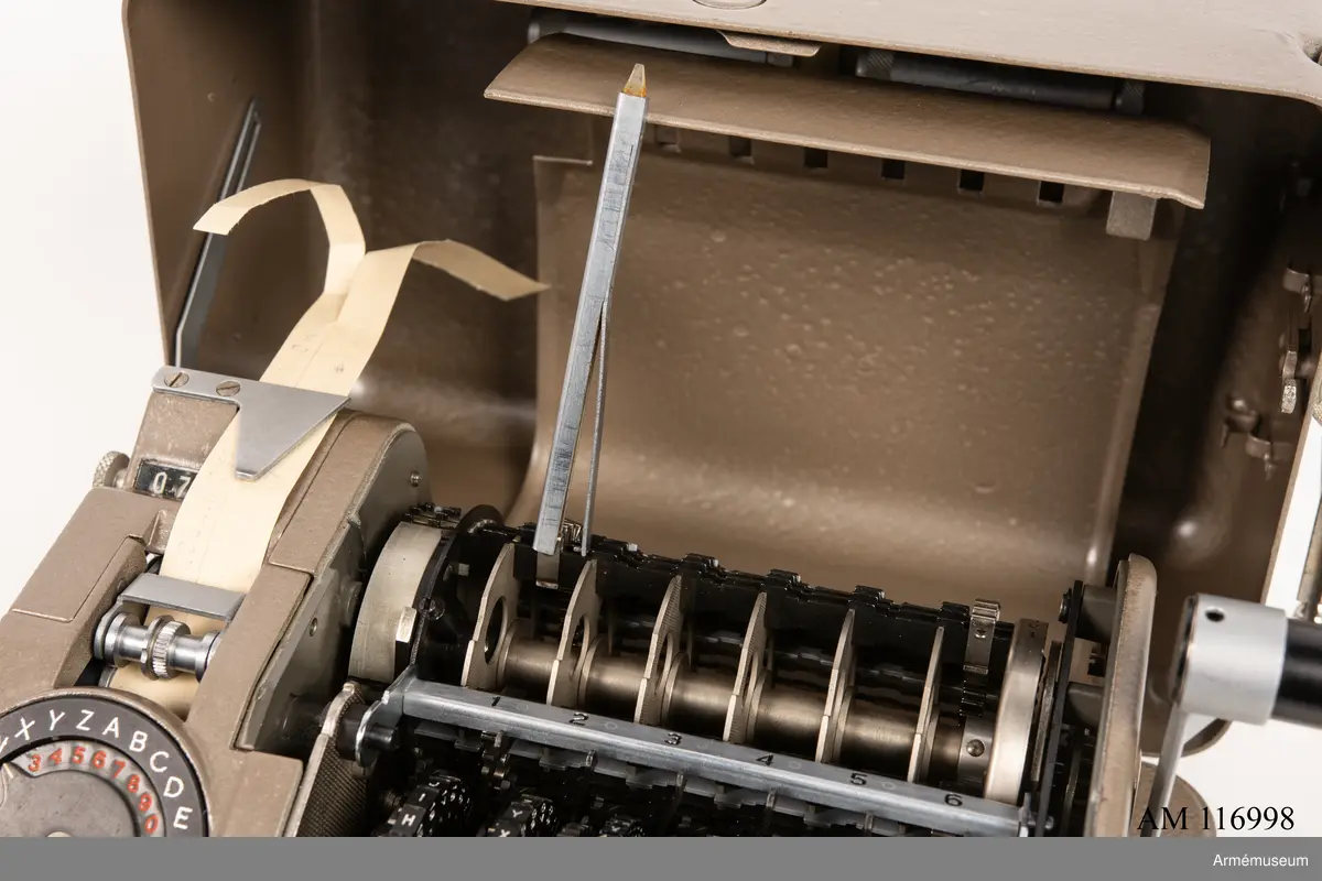Med nycklar.

Text på liten bricka på högra sidan: "Type CX-52 No 10924, Manufactured for Crypto AG Zug Switzerland by AB Cryptoteknik Stockholm Sweden".

Under krypteringsapparatens lock finns en liten vit lapp märkt "MV Boden Avd 4 Översyn 11 68", dvs troligen Miloverkstaden Boden, november 1968. 

De fysiska nycklarna ger olika access till användarna. Den nyckel med ett hack i ovansidan på nyckeln öppnar endast yttre luckan och dras sedan ut. Därpå förs nyckeln med två hack på nyckelörat in vilket gör att inre luckan går att öppna. Den senare nyckeln ger access till själva innandömet och rotorhjulen går att ta ut efter att sprinten på högra sidan dragits ut.
