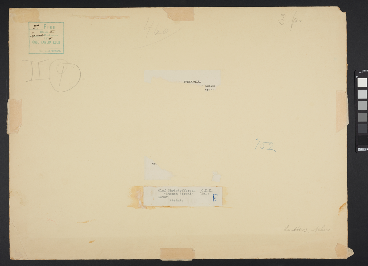 En strand ved sjøen som er dekket av store steiner. Ute på vannet ved horisonten er det en seilbåt, og bak den strekker det seg en landmasse med myke fjell.